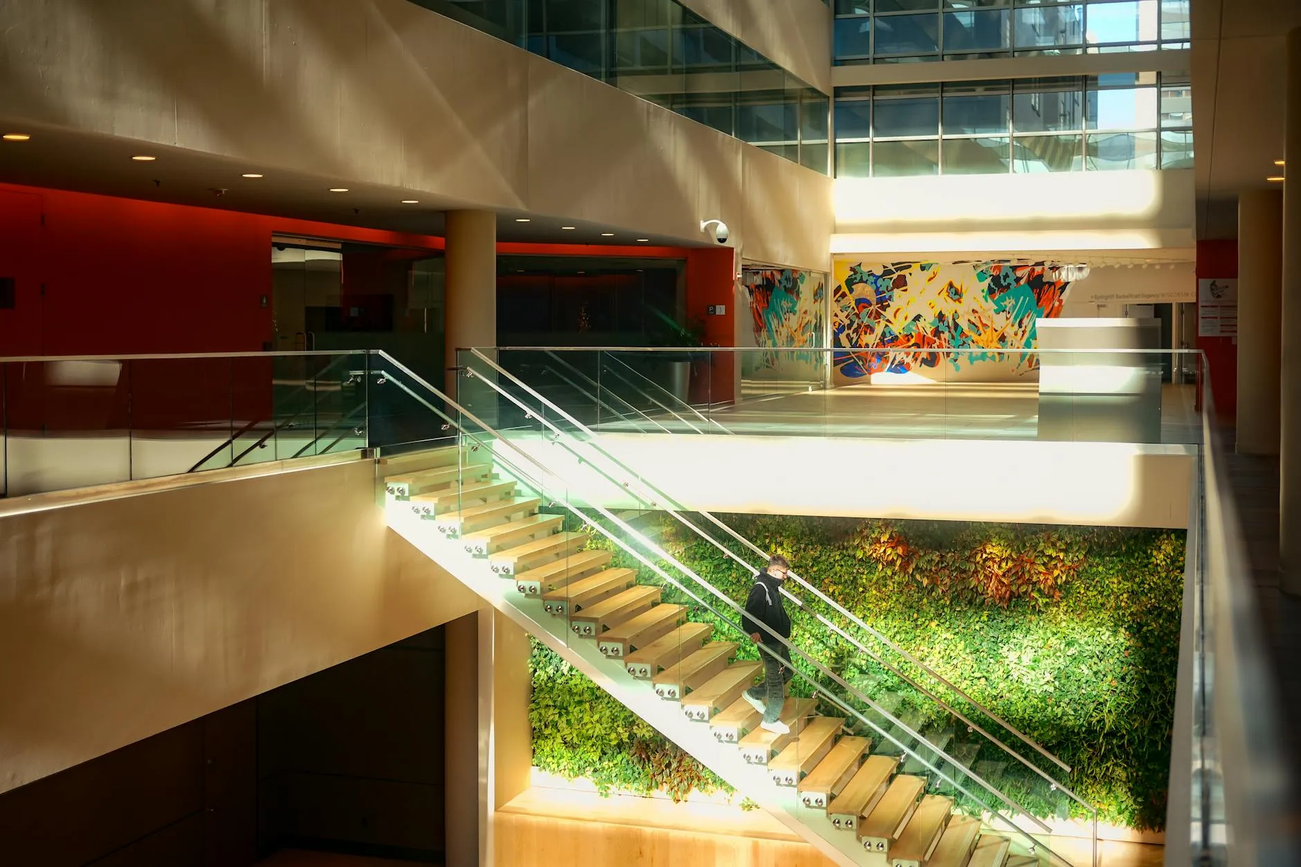 Bright building atrium with glass railings, a living wall, and vibrant artwork